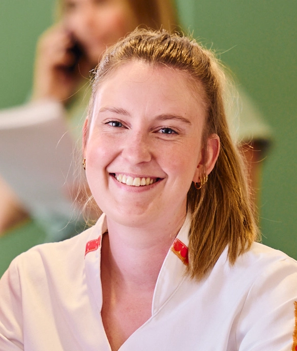 Lachende persoon in witte werkjas met groene achtergrond, close-up portret.