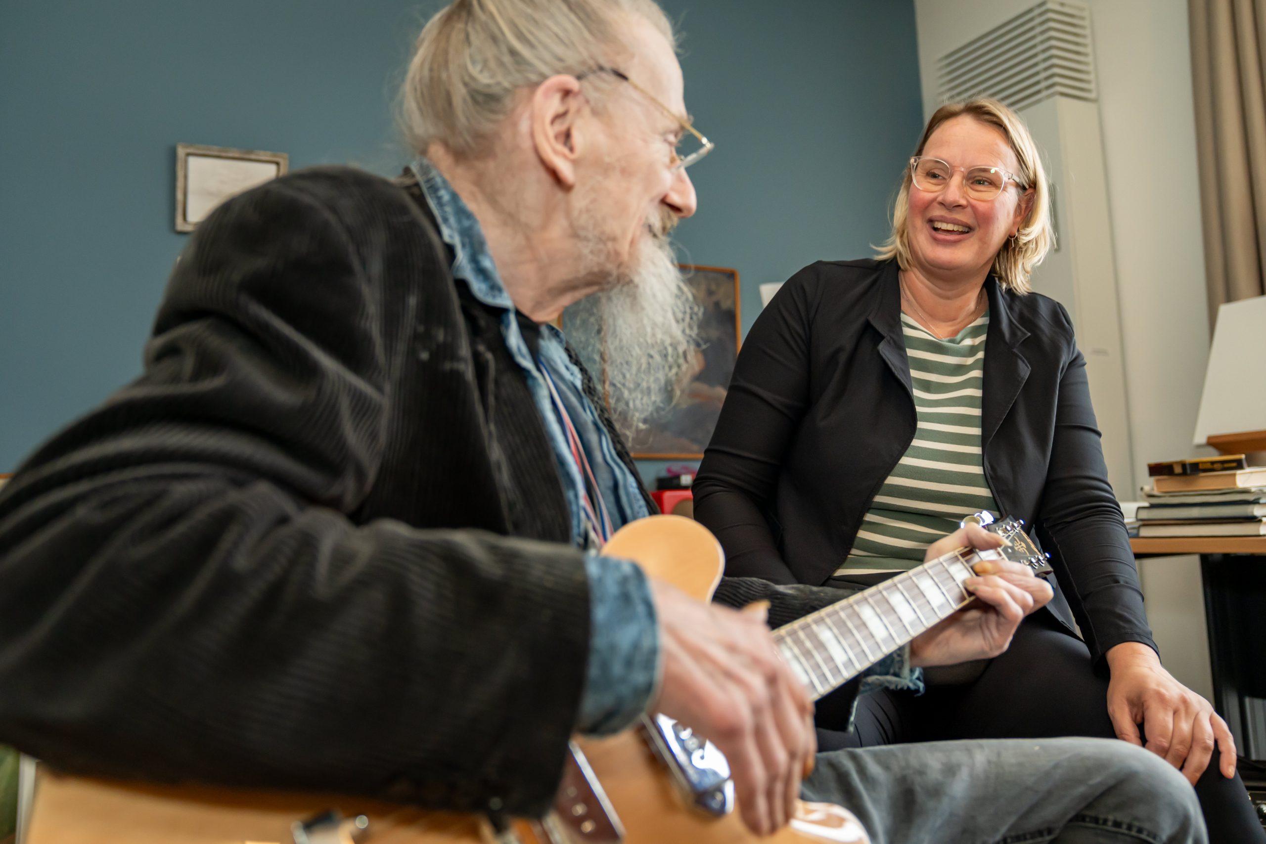 Man speelt elektrische gitaar terwijl vrouw naast hem lacht in een kamer